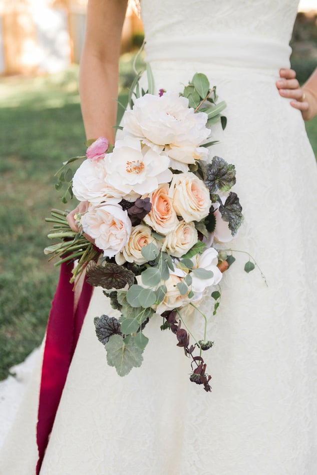 Bride in Wedding Gown Holding a Bouquet of Flowers Outdoors